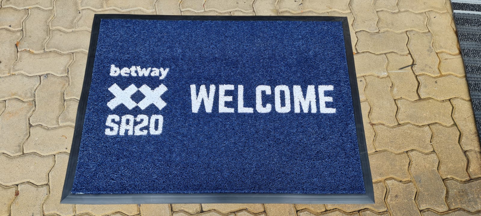 Blue custom spaghetti logo mat 2000mm x 1000mm at a double door entrance